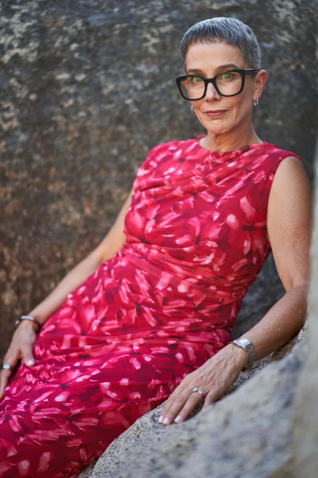Woman in red dress leaning against a rock