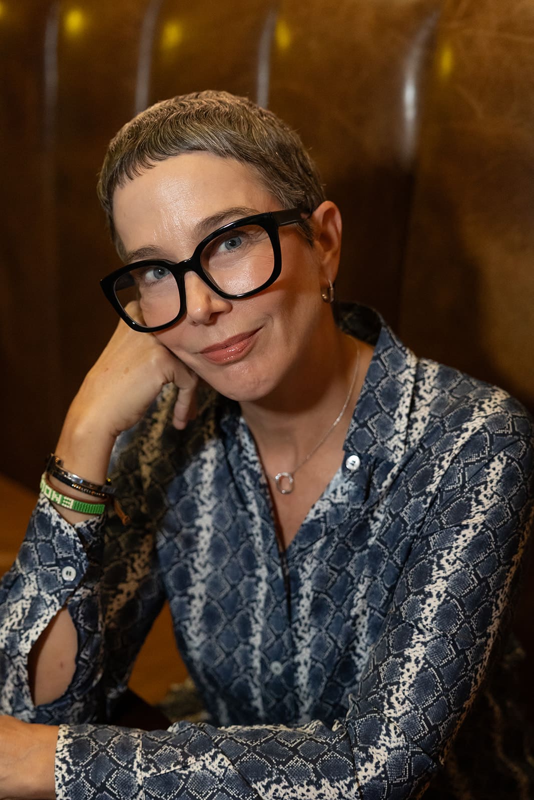 woman wearing glasses leaning on her hand looking at camera